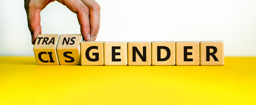 Transgender or cisgender symbol. Male hand flips wooden cubes and changes word 'cisgender' to 'transgender'. Beautiful yellow and white background, copy space. Transgender or cisgender concept.