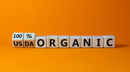 100 percent organic symbol. Fliped wooden cubes and changed words USDA organic to 100 percent organic. Beautiful orange background, copy space. Business, healthy lifestyle 100 percent organic concept.