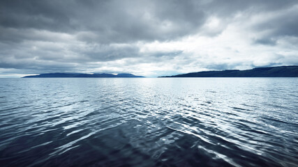 Panoramic view of the rocky river shores from the water. Trees, hills and mountains in the...