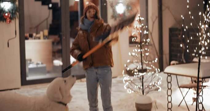 Young woman playing with her white dog, throwing a snow with a shovel, having fun on the backyard during winter holidays. Slow motion video