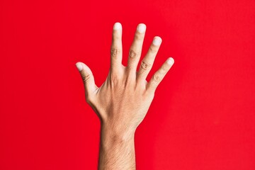 Arm of caucasian white young man over red isolated background counting number 5 showing five fingers