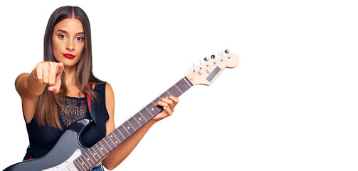 Obraz premium Young hispanic woman playing electric guitar pointing with finger to the camera and to you, confident gesture looking serious