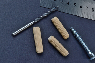 furniture assembly fittings, ruler and drill. lie on a dark background. close-up.