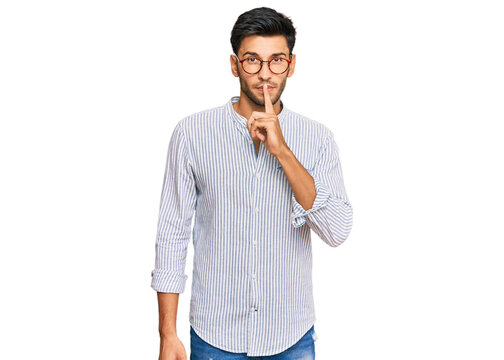 Young handsome man wearing casual clothes and glasses asking to be quiet with finger on lips. silence and secret concept.