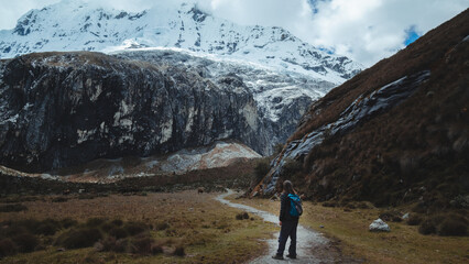 Fototapeta premium Hiker looks the snowy peaks Chakrarahu on the way to Lagoon 69 in Cordillera Blanca, Peru.