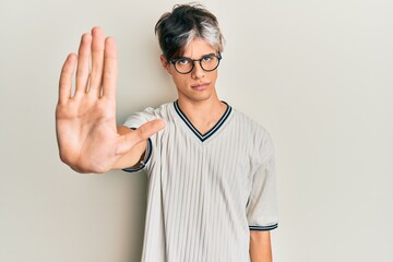 Young hispanic man wearing casual clothes and glasses doing stop sing with palm of the hand....