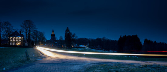 Kleines Dorf, Egen, am Abend mit vorbeifahrendem Auto 
