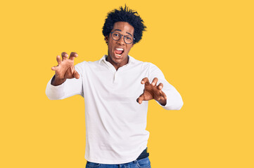 Handsome african american man with afro hair wearing casual clothes and glasses smiling funny doing...
