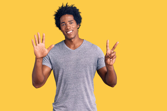 Handsome african american man with afro hair wearing casual clothes showing and pointing up with fingers number seven while smiling confident and happy.