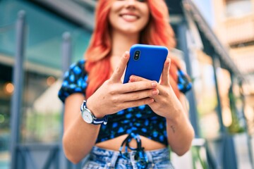 Young redhead girl smiling happy using smartphone at the city.