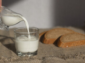 
milk is poured into a glass and rustic bread