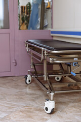Empty mechanical trolley for patients in the hospital corridor. Ambulance trolley. Trolley for transporting patients. Medical equipment and supplies.