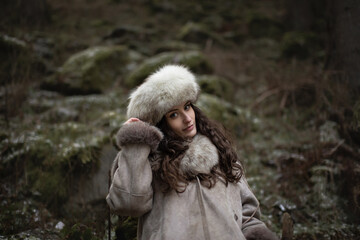 Portrait of a woman wearing fur hat and leather jacket.Shot in forest surroundings.