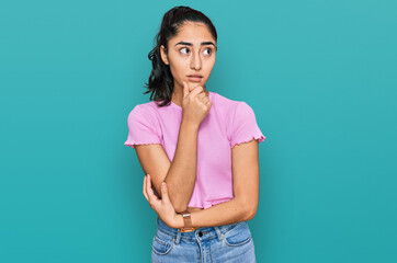 Hispanic teenager girl with dental braces wearing casual clothes thinking worried about a question, concerned and nervous with hand on chin