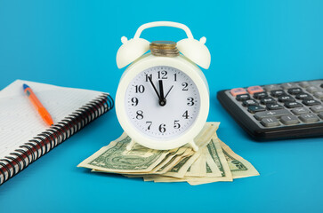 Time and money. Save money for future preparation. Alarm clock and money and calculator on a blue background. Money concept.