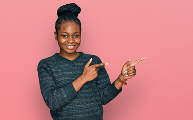 Young african american woman wearing casual clothes smiling and looking at the camera pointing with two hands and fingers to the side.