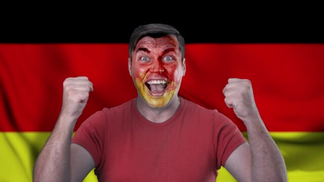 A screaming German cheerleader with a face painted in the color of the German flag.