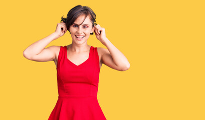 Beautiful young woman with short hair wearing casual style with sleeveless shirt smiling pulling...