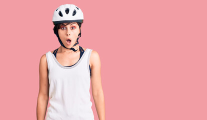 Beautiful young woman with short hair wearing bike helmet scared and amazed with open mouth for surprise, disbelief face