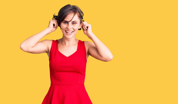 Beautiful young woman with short hair wearing casual style with sleeveless shirt smiling pulling ears with fingers, funny gesture. audition problem