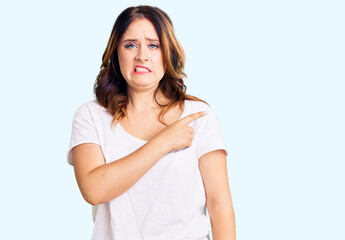 Young beautiful caucasian woman wearing casual white tshirt pointing aside worried and nervous with...