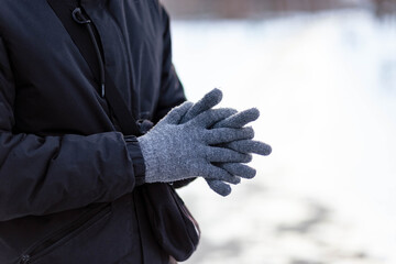 The guy in gloves warms his hands. The guy warms his hands. Hands in gray winter gloves. The palm with the glove in the snow.