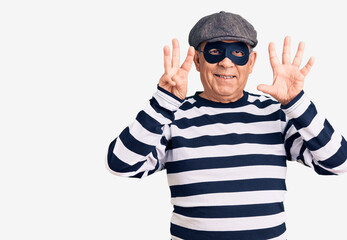 Senior handsome man wearing burglar mask and t-shirt showing and pointing up with fingers number eight while smiling confident and happy.