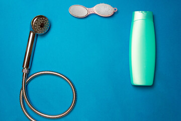 Showering. Shower head with bath brush, bottle of shampoo on a blue background. Top view