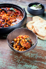 Modern style slow cooked Lebanese vegetarian eggplant stew maghmour served with chickpeas and pita bread as close-up in a rustic design bowl