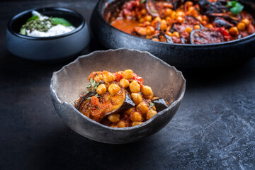 Modern style slow cooked Lebanese vegetarian eggplant stew maghmour served with chickpeas and yoghurt as close-up in a rustic design bowl