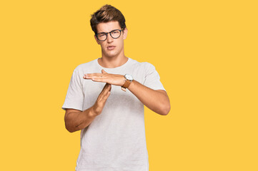 Handsome caucasian man wearing casual clothes and glasses doing time out gesture with hands, frustrated and serious face