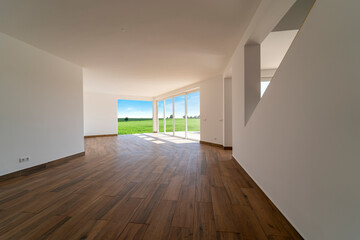 Fototapeta na wymiar Empty room with dark wooden floating laminate flooring. House interior, wide bedroom space. Newly coutryside apartment or house with nature view. Wood floor. Real state or property management
