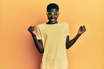 Young african american man wearing casual clothes and glasses celebrating surprised and amazed for success with arms raised and open eyes. winner concept.