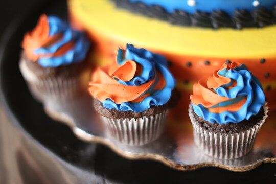 Colorful chocolate cupcake with cake behind, muffin de chocolates decorados con crema batida de colores