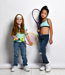 Little tennis player isolated studio portrait shot on white background. Caucasian and Asian girls...