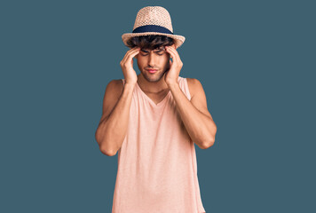 Young hispanic man wearing summer hat with hand on head for pain in head because stress. suffering migraine.