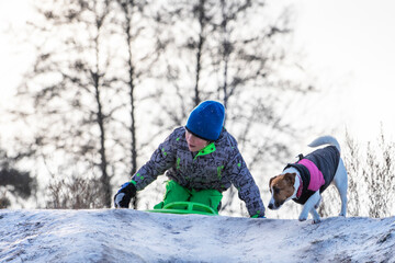 happy boy with jack russell terrier descends from a snowy mountain, horizontal.