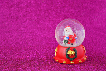Snow globe with Santa Claus on a pink background. Cozy and festive New Year mood.