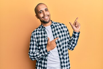 Hispanic adult man wearing casual clothes smiling and looking at the camera pointing with two hands and fingers to the side.