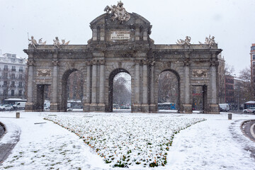 Madrid, Spain- January 9, 2021: Puerta de Alcal&aacute; de Madrid covered by snow and cold from storm Filomena. Great snowfall in Madrid. Snow storm.