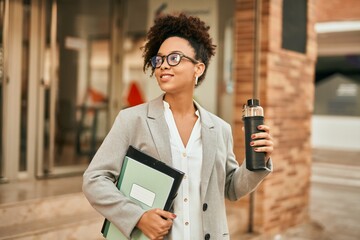 Young african american businesswoman holding bottle of water at the city.