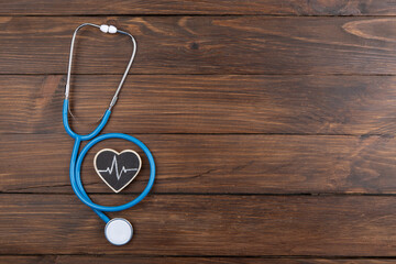 Workplace of a doctor. Stethoscope and little heart on wooden desk background