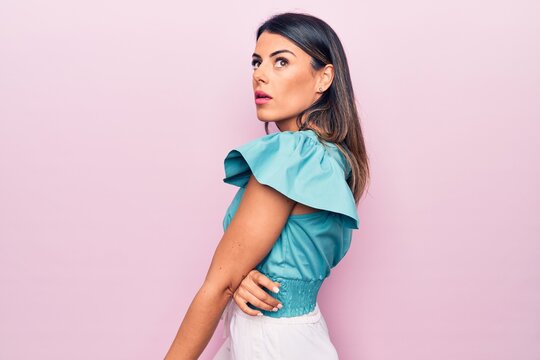 Young beautiful brunette woman standing over isolated pink background