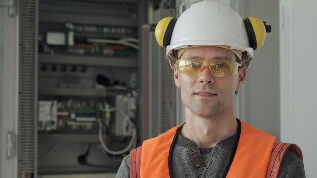 Portrait of a young male, energy engineer, next to an electrical cabinet