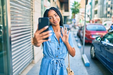 Fototapeta premium Young african american woman smiling happy doing video call using smartphone at the city.