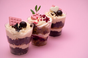 Sweet small homemade trifle dessert with custard, chocolate, nuts and fruits and decorations and cream cheese.