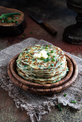 a stack of pancakes  with herbs on wooden plate