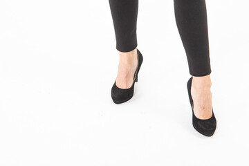 Close up view to female legs in black shoes and black leggings isolated on white background