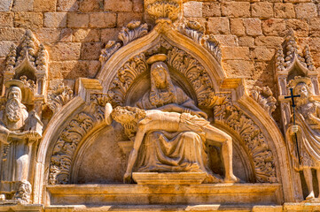 Fototapeta na wymiar A religious sculpture composition at entrance to the medieval church in Dubrovnik, Croatia.