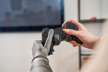 Woman with artificial limb holding gamepad and playing game
